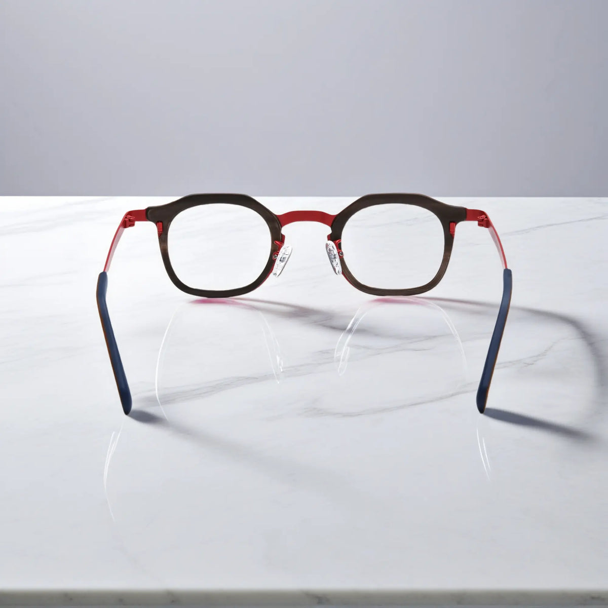 Rear view of VoyueLens Crimson Drift eyeglasses showing a warm red acetate front with amber pattern and clean titanium temples.