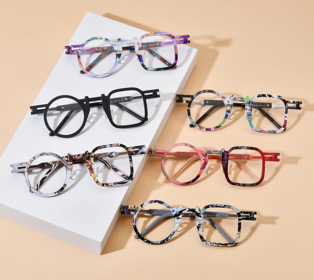 Barledear asymmetric titanium eyeglasses collection group image showing Prism Violet, Obsidian Black, Marble White, Storm Gray, Crimson Fade, and Amber Mosaic Brown variants