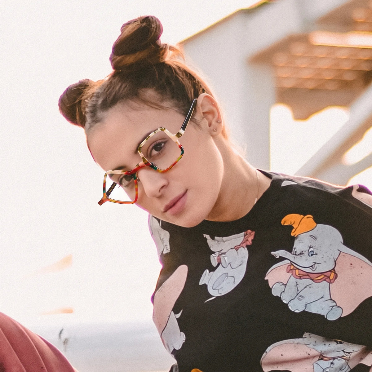 Adult model wearing Barledear Amber Mosaic asymmetric geometric acetate eyeglasses in a warm-toned creative fashion portrait.