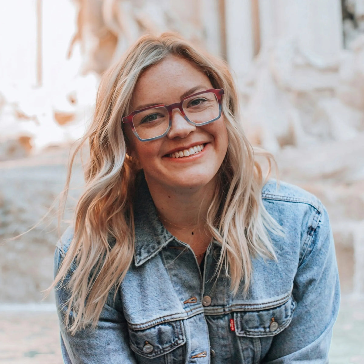 Model wearing Barledear Crimson Smoke red and gray square acetate eyeglasses in a modern lifestyle portrait