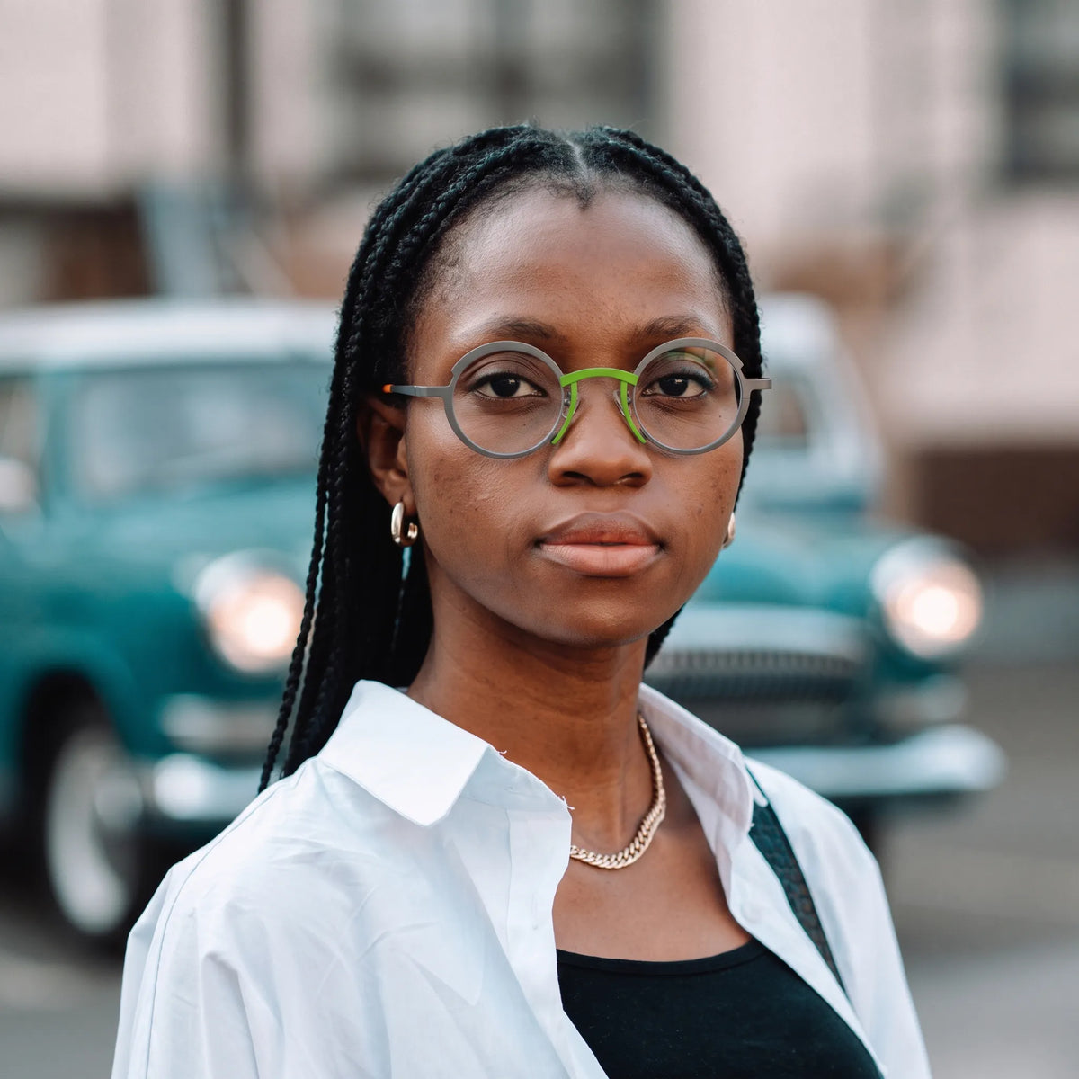 Model wearing Barledear Graphite Gray Citrus Orange titanium round eyeglasses worn in a stylish lifestyle portrait showing the medium-fit frame