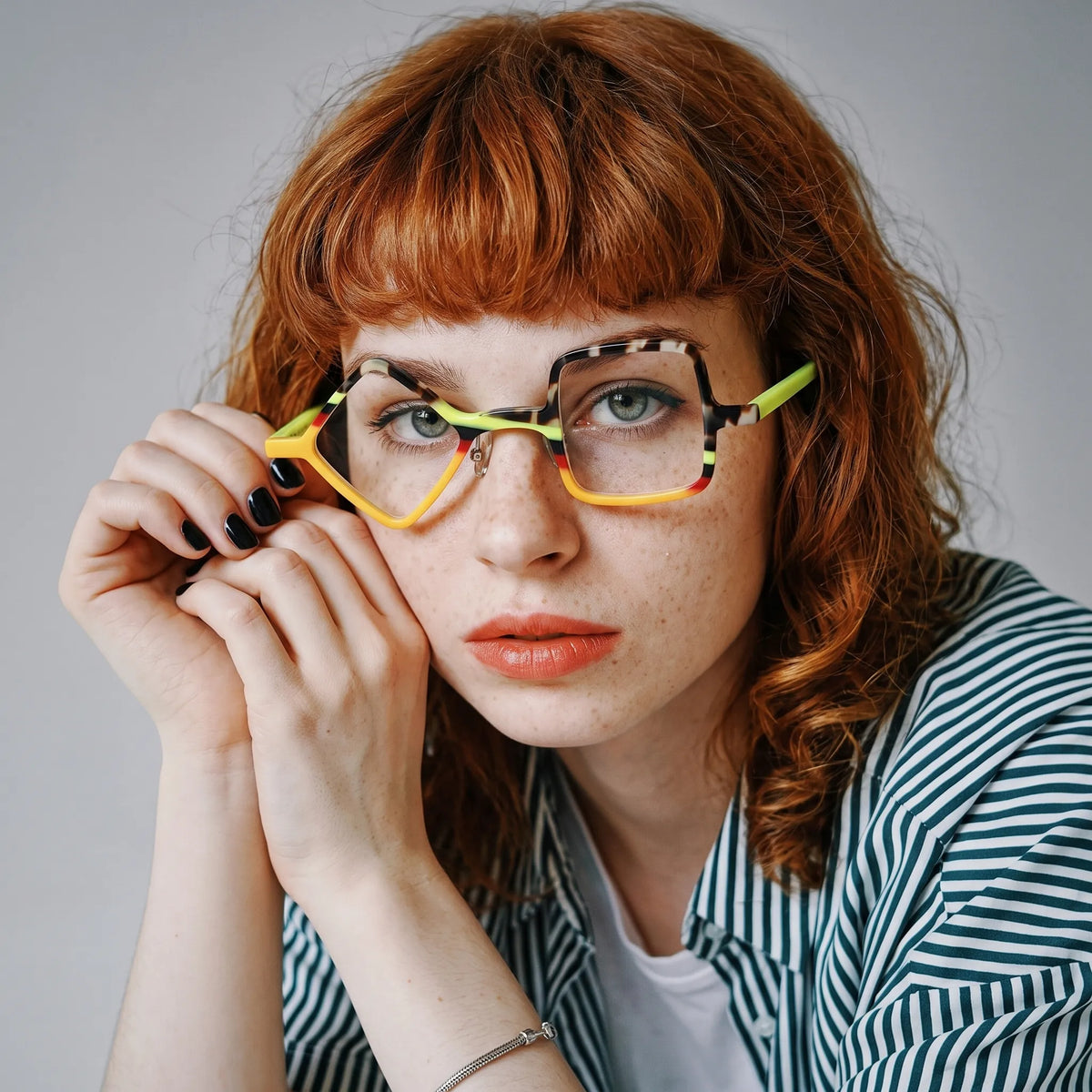 Adult model wearing Barledear Neon Tortoise asymmetric geometric acetate eyeglasses in a vibrant fashion-forward lifestyle portrait.