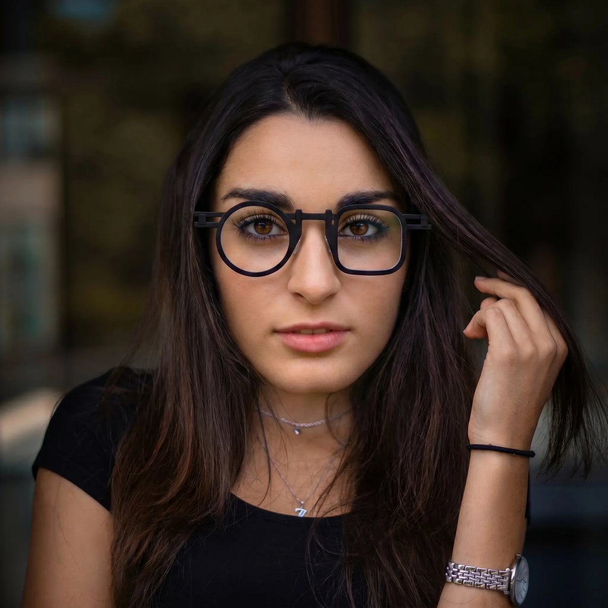 Model wearing Barledear Obsidian Black eyeglasses in a lifestyle portrait with asymmetric geometric titanium frame