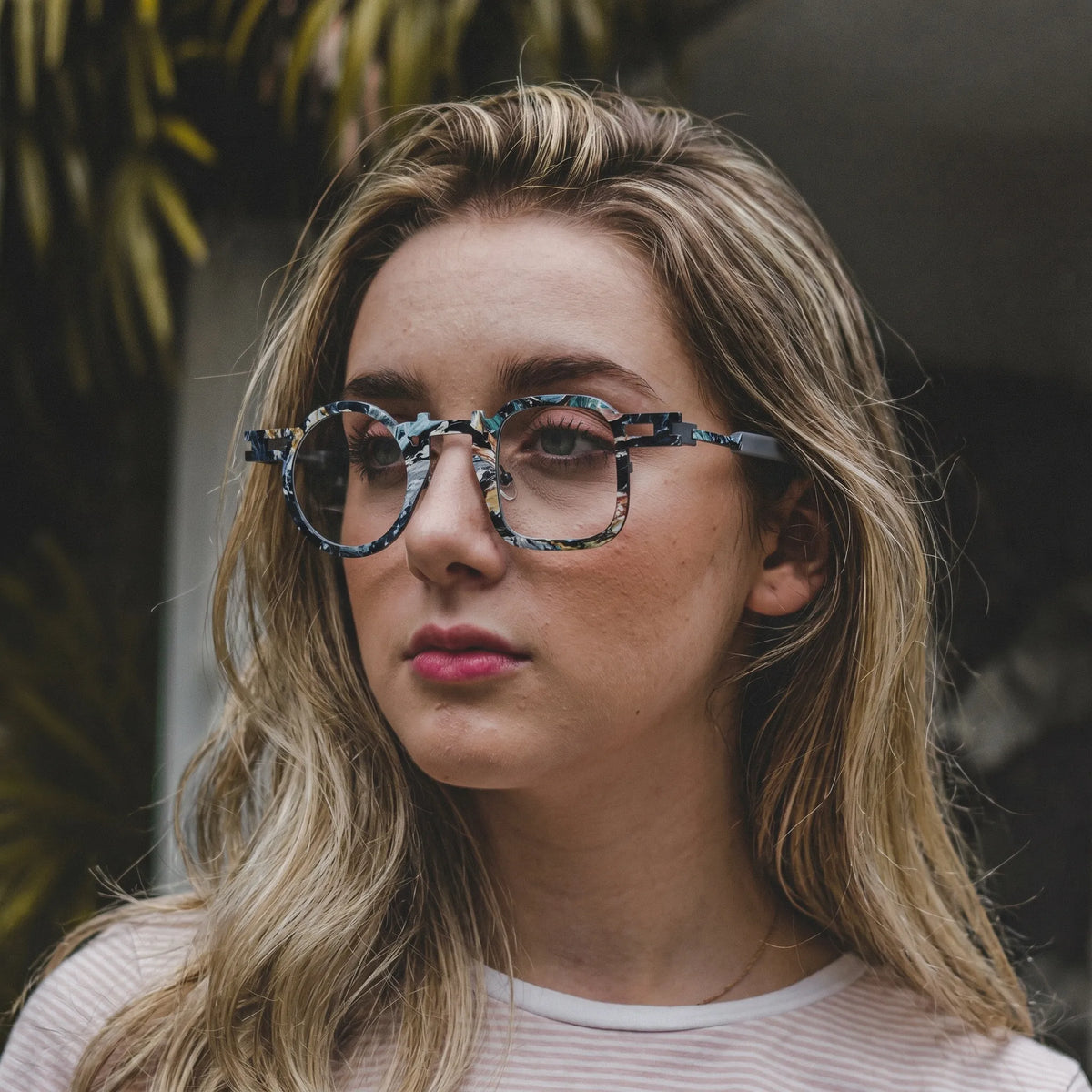 Model wearing Barledear Storm Gray eyeglasses in a lifestyle portrait with asymmetric geometric titanium frame