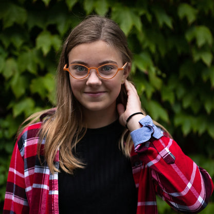 Model wearing Barledear Tangerine Bloom oval titanium eyeglasses in a lifestyle portrait