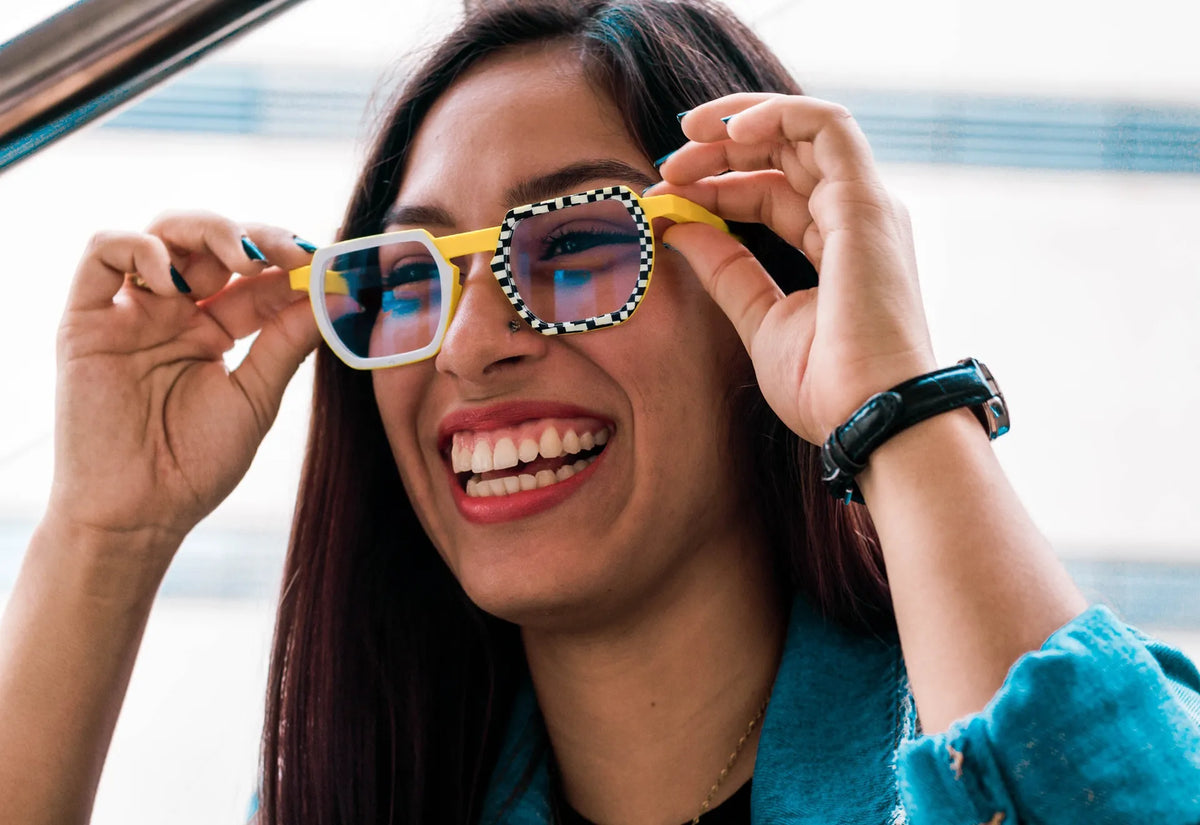 Smiling woman wearing colorful VoyueLens yellow glasses with blue lenses and checkered rims
