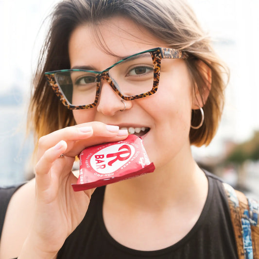 Female model wearing VoyueLens emerald tortoise cat-eye glasses, showcasing bold acetate frame in fashion-forward outdoor lifestyle setting