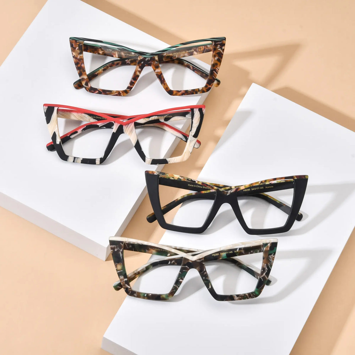 VoyueLens oversized cat-eye glasses full color collection, showcasing four unique acetate frames including Emerald Tortoise, Scarlet Ivory Feather, Black-Blue Accent, and Olive Tortoise. This top-down group view highlights the bold butterfly frame design, premium acetate construction, and stylish color options for fashion-conscious women and professionals.
