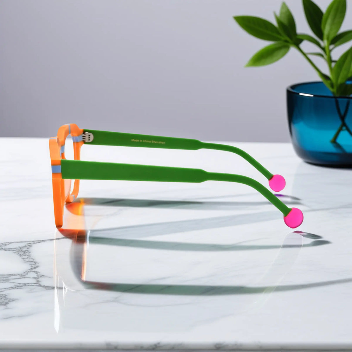 Side view of VoyueLens Citrus Pop eyeglasses showing vibrant orange frame, green temples, and pink tips