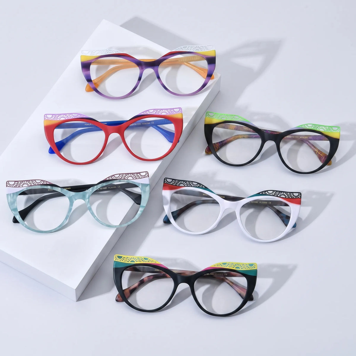 Group display of VoyueLens VL19365 cat-eye eyeglasses in six vibrant gradient variants: Amethyst Sunrise, Scarlet Horizon, Ice Coral, Aqua Frost, Citrus Tortoiseshell, and Crimson Nebula. Bold butterfly frames with lace-patterned upper edges shown on a turquoise background.