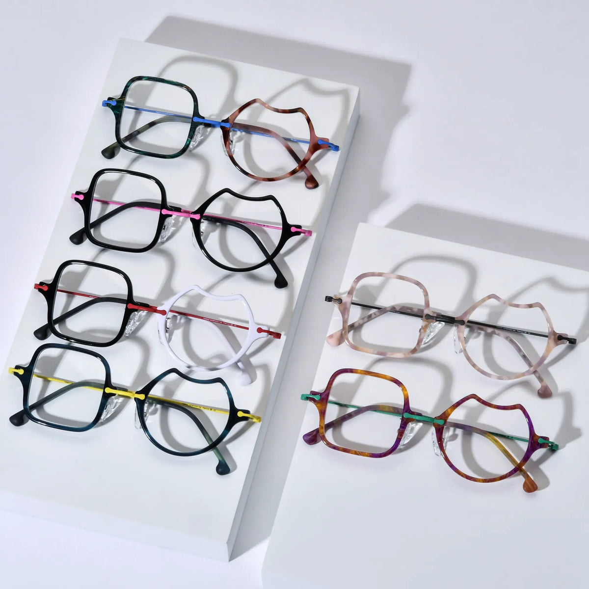 Top-down view of all VoyueLens VL185842 Abstract Harmony Eyeglasses color variants including Ocean Brick, Frosted Crimson, Shell Pink, Jungle Carnival, Electric Olive, and Neon Bloom arranged on display platforms.
