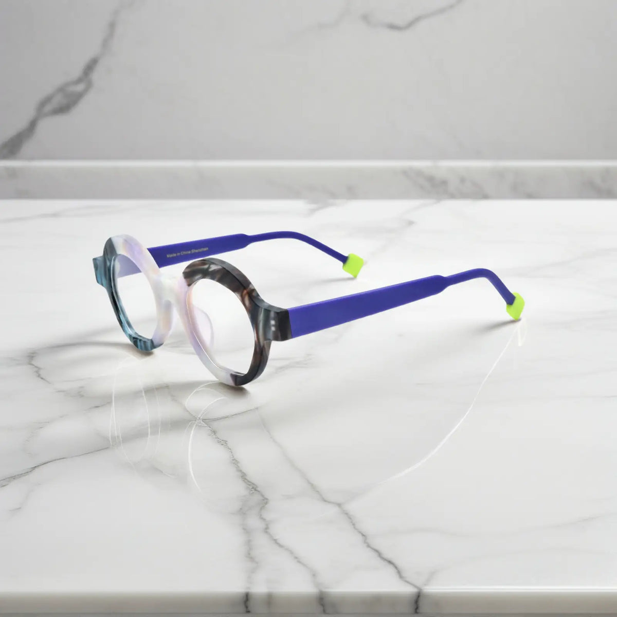 Side angle showing Ice Marble variant with geometric frame lines and smooth matte acetate material