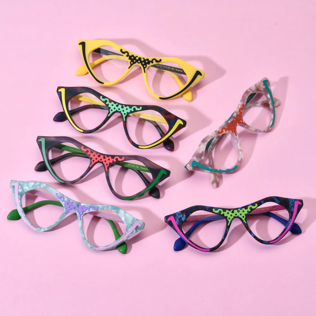 Group shot of six VoyueLens Retro Pixel Cat-Eye Glasses in assorted colors including Cyber Yellow, Color Burst, Jungle Moss, Mint Sorbet, Blush Marble, and Neon Pop displayed on a pastel pink background.