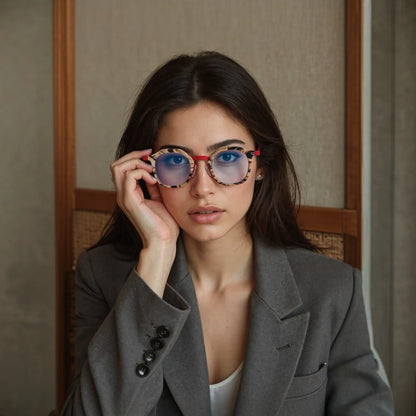 Model wearing VoyueLens Crimson Drift square eyeglasses with a warm red acetate front with amber pattern and clean titanium temples.