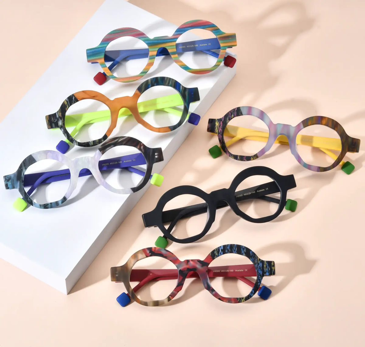 Top-down display of VoyueLens VL19355 polygon eyeglasses in all six color variants including Rainbow Stripe, Lime Tortoiseshell, Ice Marble, Aurora Fade, Charcoal Black, and Crimson Nebula, featuring matte acetate frames with contrasting temples, ideal for lightweight prescription eyewear.