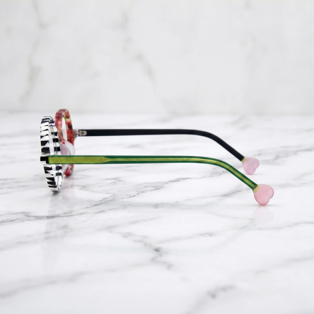 Side profile of Checker Red Pop variant, showcasing frame thickness and temple arm structure. Bold red and black asymmetrical frame with heart and round lenses.