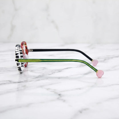 Side profile of Checker Red Pop variant, showcasing frame thickness and temple arm structure. Bold red and black asymmetrical frame with heart and round lenses.